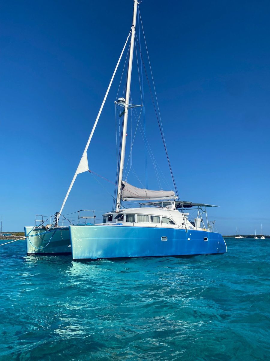 Sailing catamaran with blue hull wrap at anchor