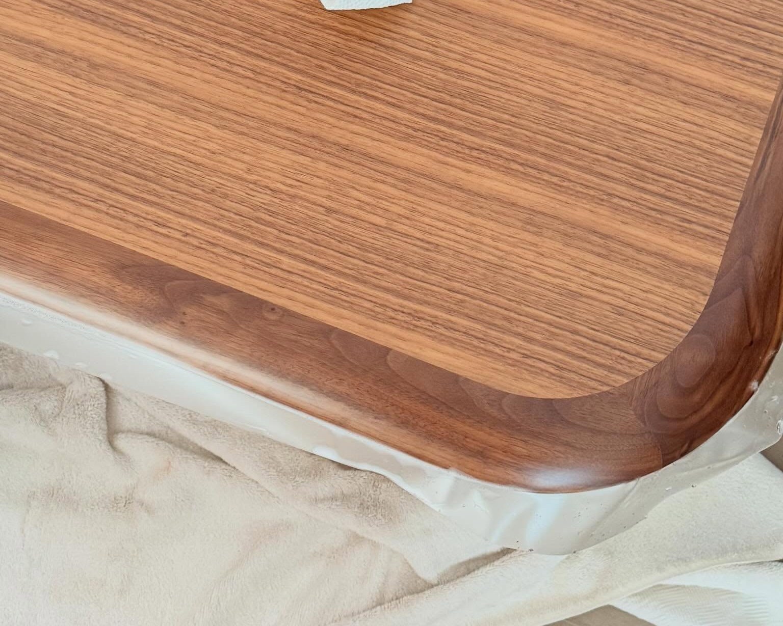 Close-up of a yacht table in rich wood grain with clear protection film being applied to the edge